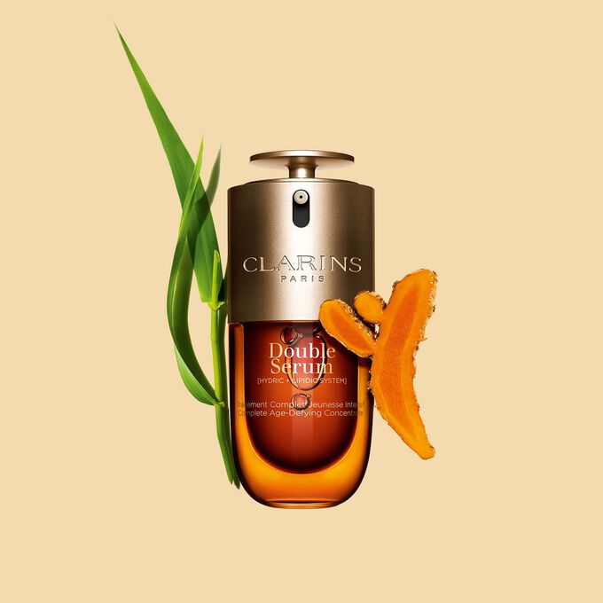 Foto de Clarins Double Serum junto a sus ingredientes, entre ellos la cúrcuma, sobre fondo dorado