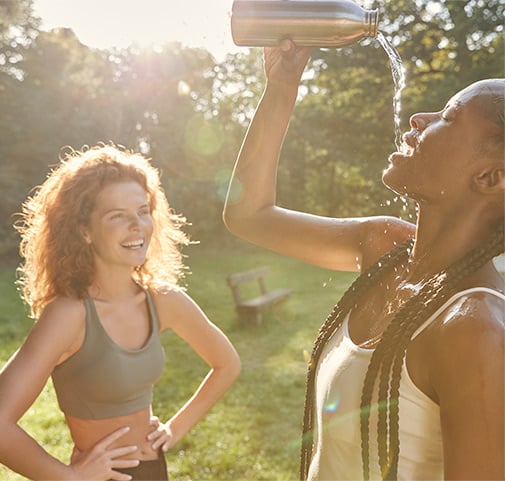 Dos mujeres jóvenes bebiendo agua y riendo